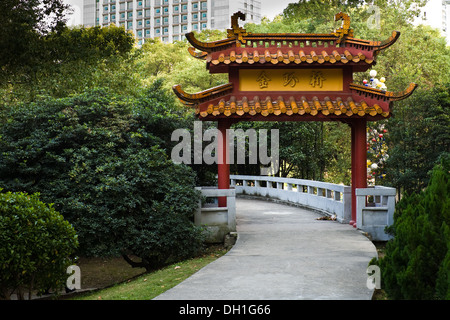 Traditional Chinese gate set in lush green park within a Chinese city Stock Photo