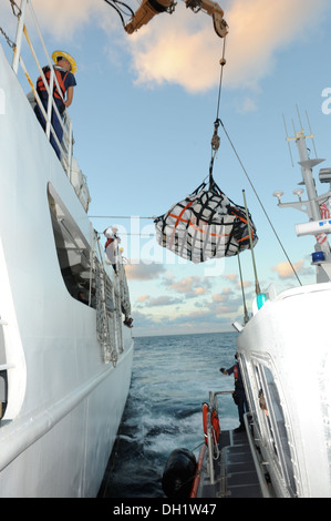 The crew aboard the Coast Guard Cutter Vigilant uses a crane to transfer contraband to a Coast Guard Station Miami smallboat crew, Oct. 11, 2013. The total load transferred was 15 bales of cocaine and 50 bales of marijuana with an estimated wholesale valu Stock Photo