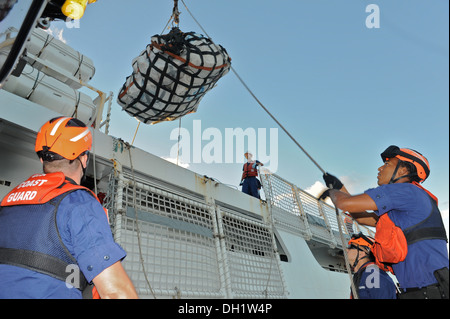 Crewmembers aboard a Coast Guard Station Miami smallboat receive an at-sea contraband transfer from the crew aboard the Coast Guard Cutter Vigilant, Oct. 11, 2013. The drugs are the results of two interdictions carried out as part of Operation Martillo. Stock Photo