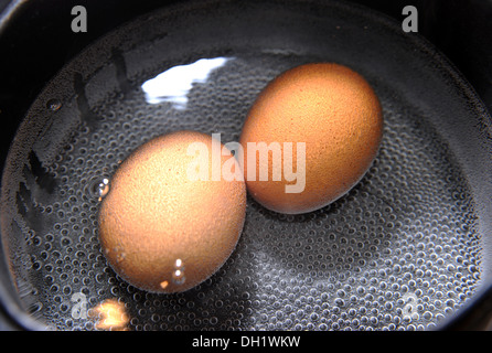 Two free range eggs boiling in a saucepan Stock Photo