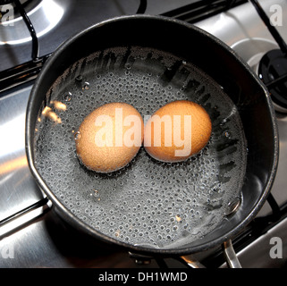 Two free range eggs boiling in a saucepan Stock Photo