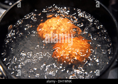 Two free range eggs boiling in a saucepan Stock Photo