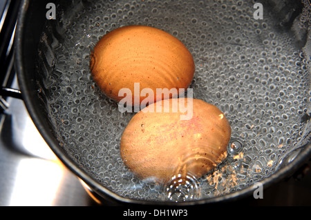 Two free range eggs boiling in a saucepan Stock Photo