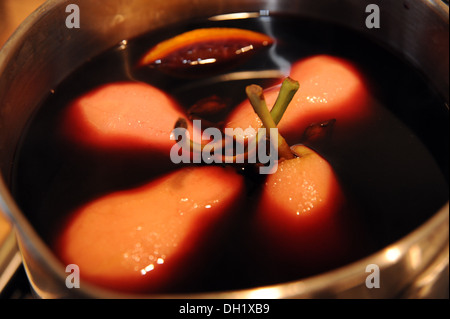 Poached pears in red wine gently cooking in a saucepan Stock Photo