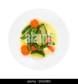 Top view of a plate with cooked zucchini, carrots and green beans in a butter sauce on a white background. Stock Photo