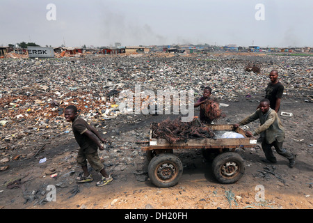 Boys pull a cart with raw copper cables from burned computers, Agbogbloshie dump site in Accra, Ghana Stock Photo