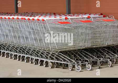 A lot of metal carts on wheels for shopping, food, stand in a row near the shop Stock Photo