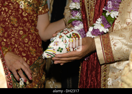 Bride and Groom dressed in all their finery celebrating their Traditional Hindu wedding taking part in traditional rituals. Stock Photo