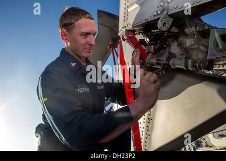 Aviation Machinist's Mate 3rd Class Mark Trevathan performs routine maintenance on an MH-60 Sea Hawk helicopter aboard the amphibious assault ship USS Kearsarge (LHD 3). Kearsarge is deployed as part of the Kearsarge Amphibious Ready Group supporting mari Stock Photo