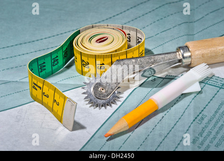Seam roller, tape measure and tailor's chalk lying on sewing pattern Stock Photo