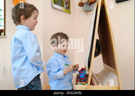 Twin boys, 4, in front of an easel Stock Photo