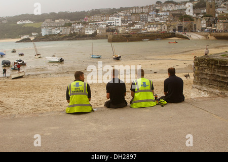 Group of construction workers, taking lunch beside the sea, at St Ives, in Cornwall, England. October 2013 Stock Photo