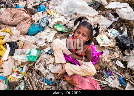 Poor Indian girl with a sack picking through an open rubbish tip ...