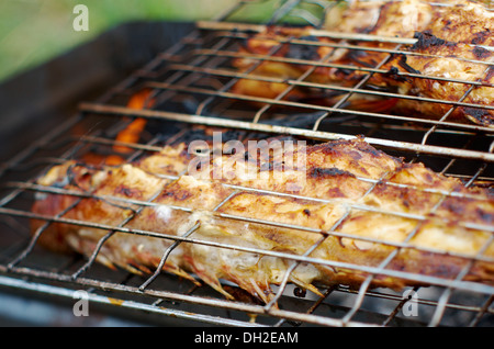 grilling sea fishes on campfire grate Stock Photo
