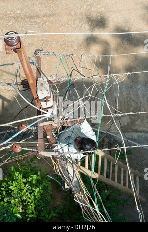 Looking down on an Indian Electrician working up an Electricity pylon in the streets of Puttaparthi, Andhra Pradesh, India Stock Photo