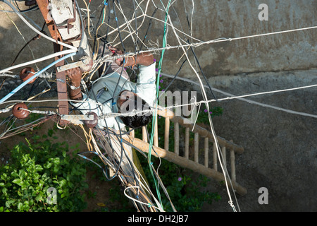 Looking down on an Indian Electrician working up an Electricity pylon in the streets of Puttaparthi, Andhra Pradesh, India Stock Photo