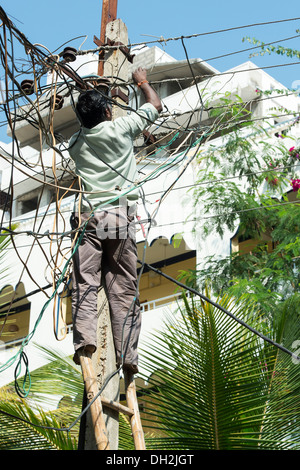 Indian Electrician working up an Electricity pylon in the streets of Puttaparthi, Andhra Pradesh, India Stock Photo