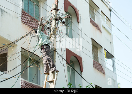 Indian Electrician working up an Electricity pylon in the streets of Puttaparthi, Andhra Pradesh, India Stock Photo