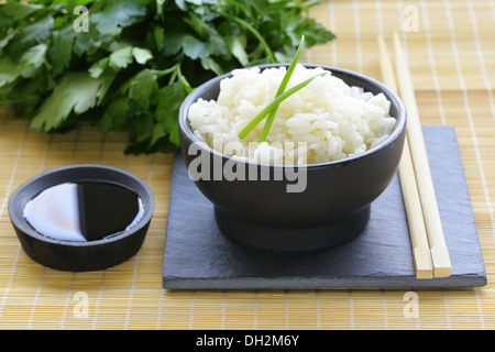 boiled white rice in a black bowl, Asian style Stock Photo
