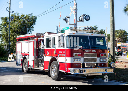 Red and white emergency fire truck vehicle parked at railroad crossing near historic downtown district of Mount Dora in Florida. Stock Photo