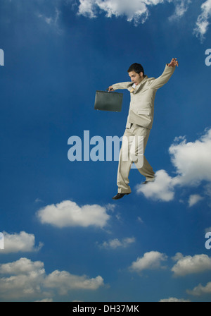 Businessman holding a briefcase and moving on clouds Stock Photo