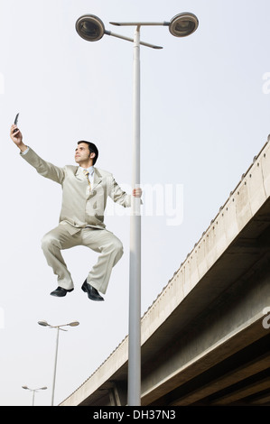 Businessman holding a street light and text messaging Stock Photo