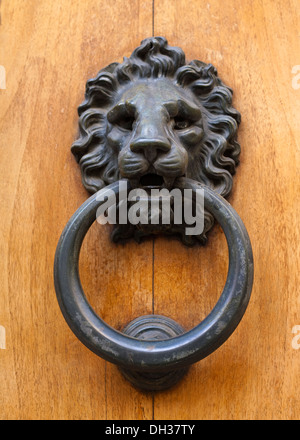 A heavy lion head style door knocker on a wooden door Stock Photo