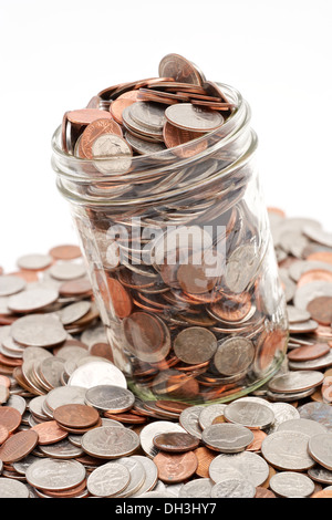 Glass mason jar full of loose pocket change spilling out on white ...