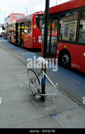 Remains of vandalised ghost bike on CS2, Barclays Superhighway Route 2 with buses close alongside Stock Photo
