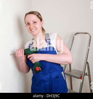 Young woman renovating her home with a drilling machine Stock Photo
