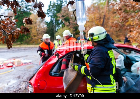 Accident - Fire brigade rescues accident Victim of a car using a hydraulic rescue tool and giving a first aid infusion Stock Photo