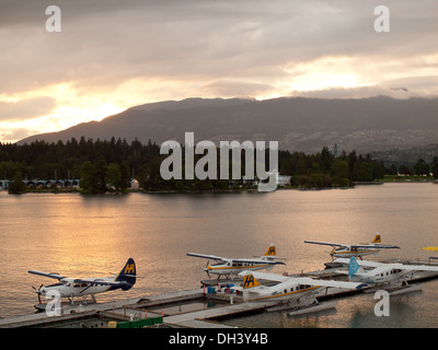 At sunset, five seaplanes are docked at the Vancouver Harbour Flight Centre, Vancouver's downtown seaplane terminal. Stock Photo