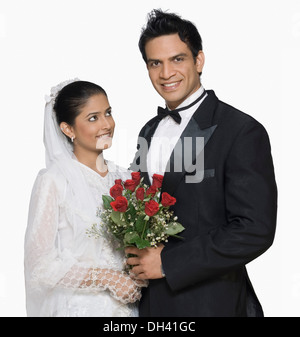 Portrait of a newlywed couple holding a bouquet of flowers and smiling Stock Photo