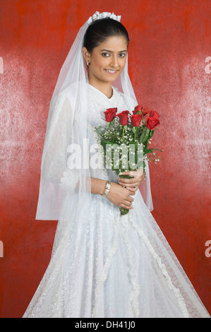 Portrait of a newlywed bride holding a bouquet of flowers and smiling Stock Photo