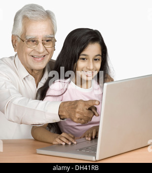 Senior man using a laptop with his granddaughter and smiling Stock Photo
