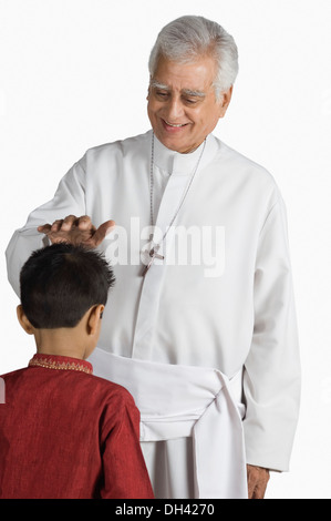 Priest blessing a boy and smiling Stock Photo