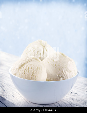 Vanilla ice-cream scoops in white cup over snow background. Stock Photo