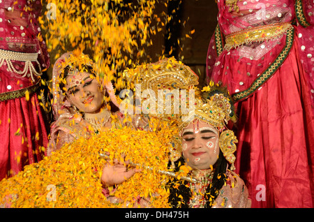 man and woman dressed as Radha Krishna dancing and flowers dropping from above in Marwar Festival Jodhpur Rajasthan India Stock Photo