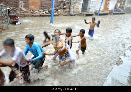 boys playing in flowing monsoon rain water on street of Jodhpur Rajasthan India Stock Photo