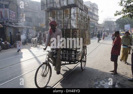 man on tricycle loaded with empty tin cans at kolkata West Bengal India Stock Photo