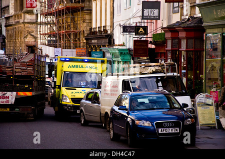 Ambulance on emergency call trying to squeeze through congested traffic on a busy street in Bath Somerset England UK Stock Photo