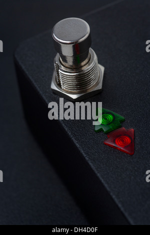 Black case with a push-button and two arrow-shaped indicator lights.   Boîtier noir avec bouton poussoir et voyants lumineux. Stock Photo