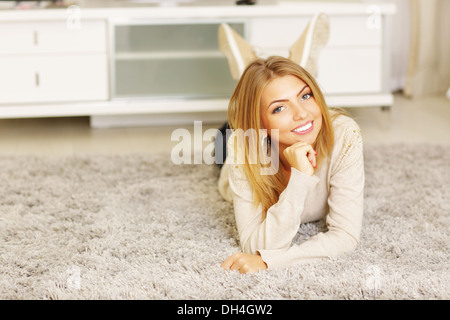 Young beautiful woman lying on the carpet at home Stock Photo