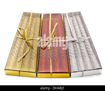 Three packs of Christmas candles red, silver and gold on white table Stock Photo
