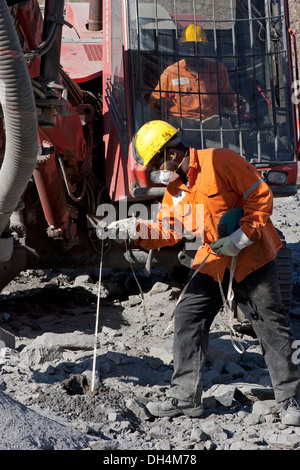 Surface pit gold mine, measuring depth of recently drilled holes before explosive charge is put in before blast, Mauritania Stock Photo