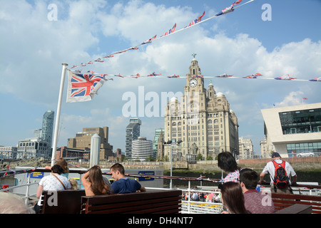 The Royal Liver building seen through flags from a Mersey ferry arriving at the Pier Head. Passengers Stock Photo