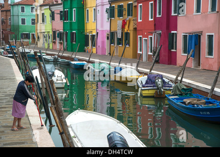 Woman cleaning the canalside pavement. Burano, Venice Lagoon, Italy. Stock Photo