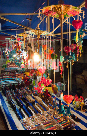 Vertical close up of wooden statues and mobiles on sale at a street market in Laos. Stock Photo