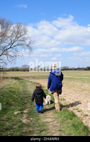 Mother, toddler and  Shih Tzu dog walking on footpath in fields. Early Spring. Stock Photo