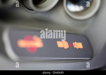 Close-up of the illuminated fasten seatbelt sign inside an airplane, selective focus on red arrow. Stock Photo